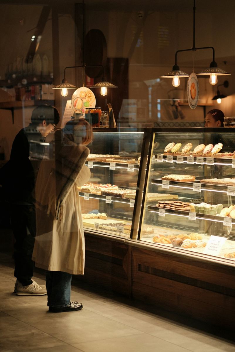 A customer standing at a glass bakery counter.