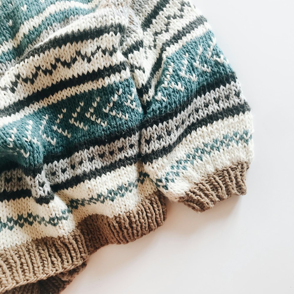 A teal, white and tan Fair Isle yoke sleeve laid flat.