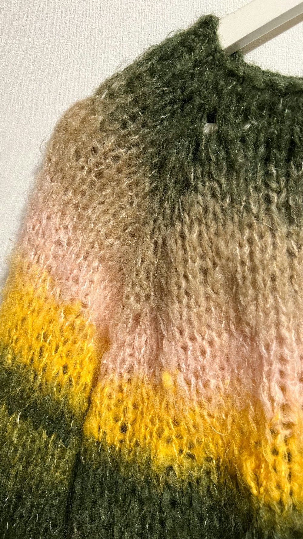 A knitted jumper fading from green to lichen gold.