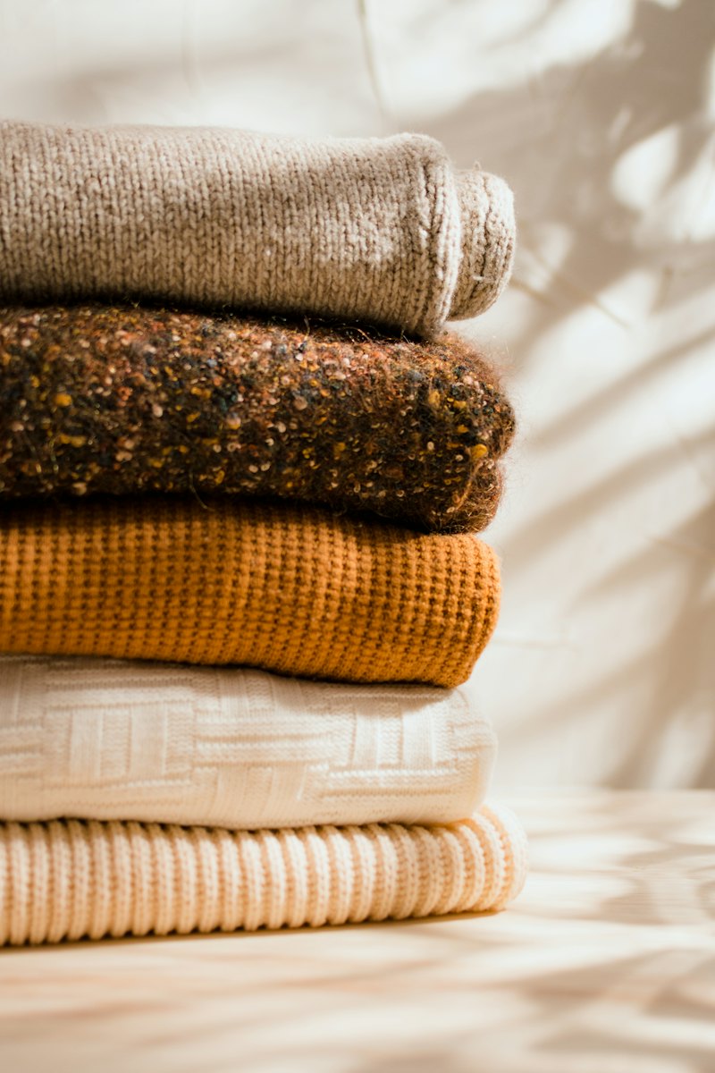 A neat stack of finished knitted jumpers in brown and orange.