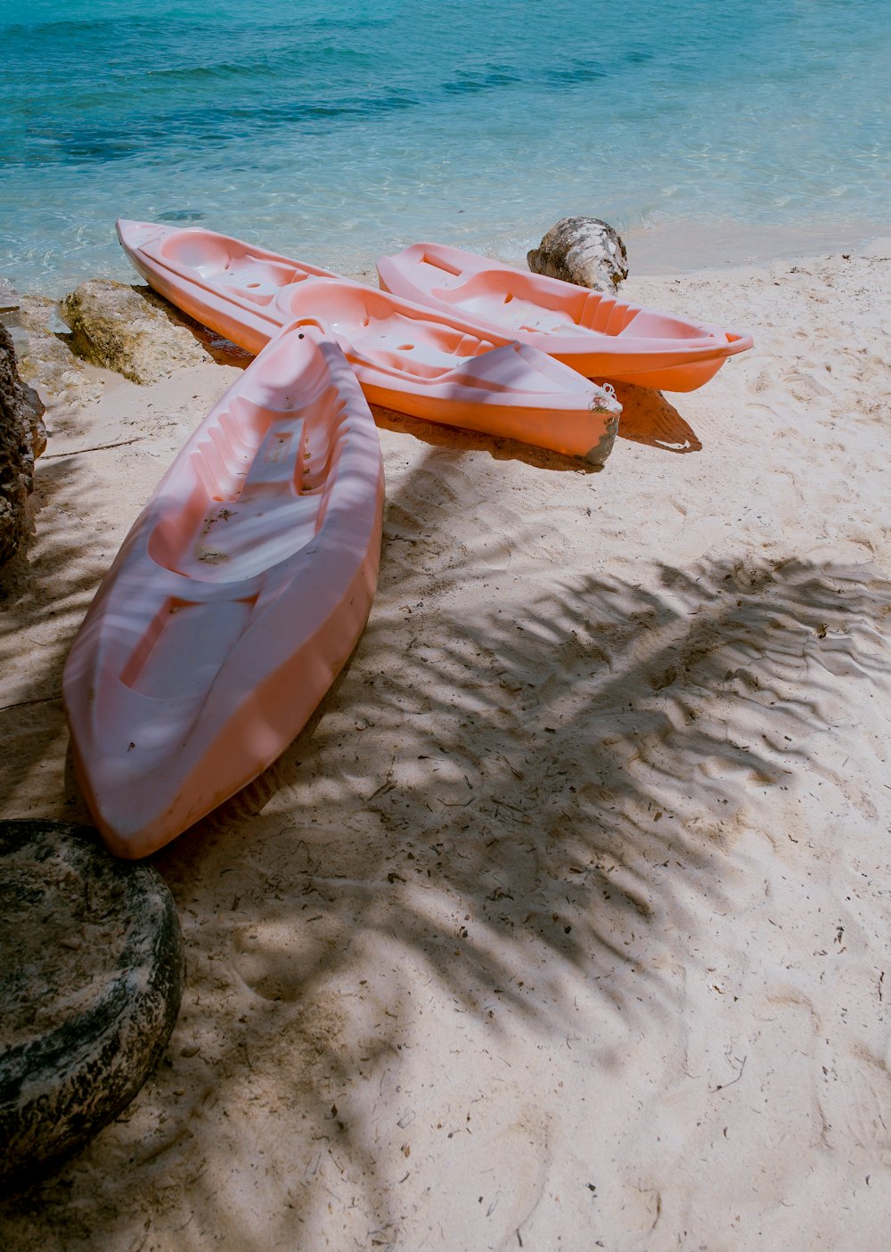 Kayaks lined up on a sandy beach.