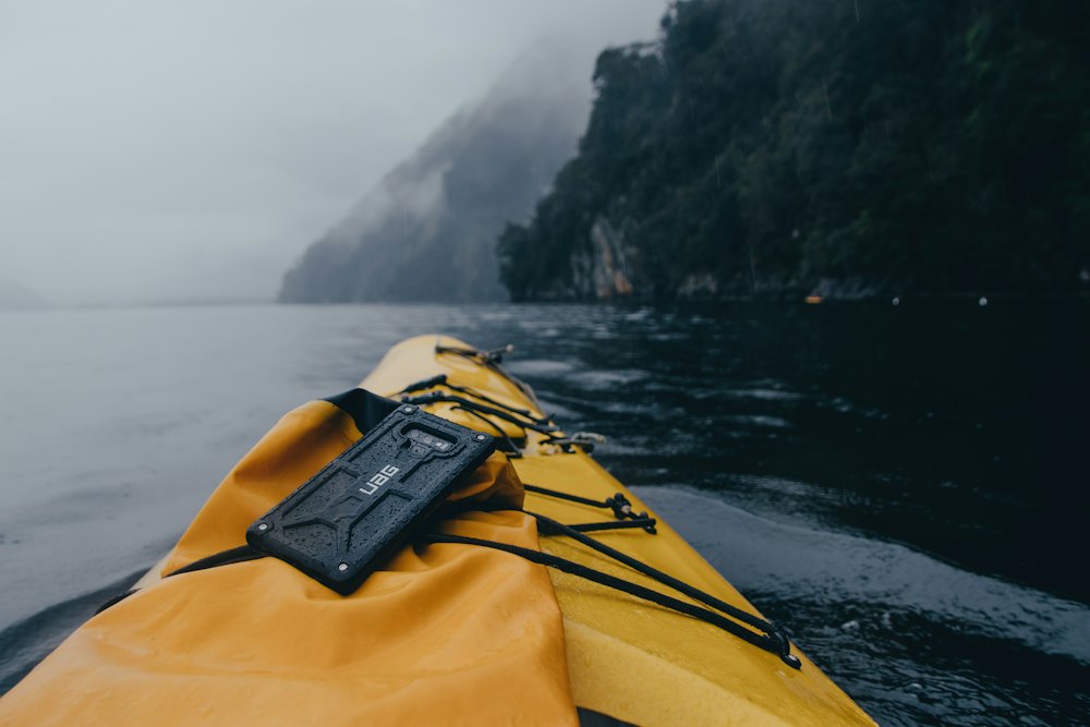 The bow of a yellow kayak with a misty coast beyond.